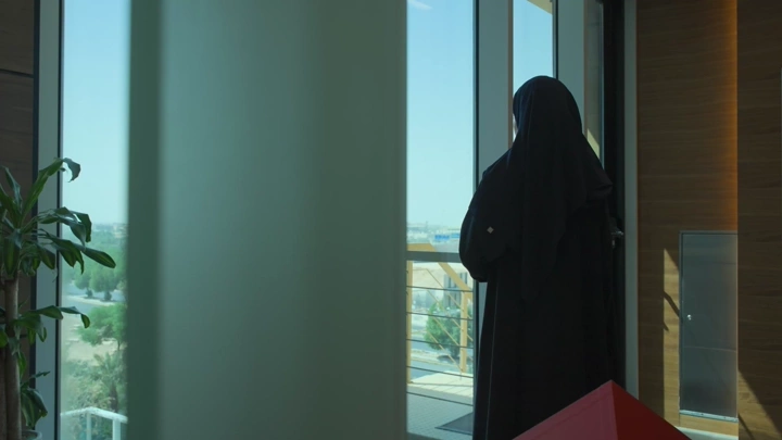 شخص يقف بجانب نافذة في مكتب حديث، لقطة داخلية.