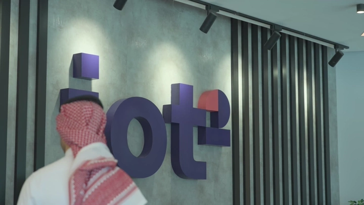 موظف يرتدي الزي التقليدي أمام شعار شركة، لقطة داخلية.