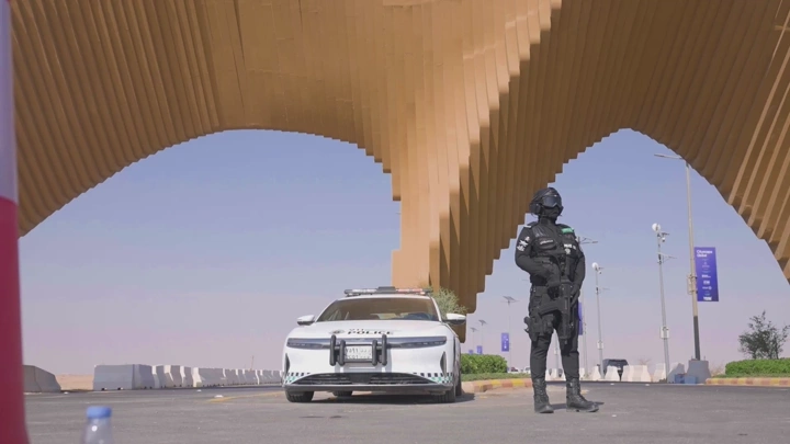 جندي يقف بجانب سيارة شرطة تحت جسر حديث، لقطة نهارية.