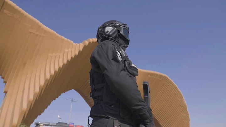 جندي بزي أسود يقف أمام هيكل معماري، لقطة من الأسفل.