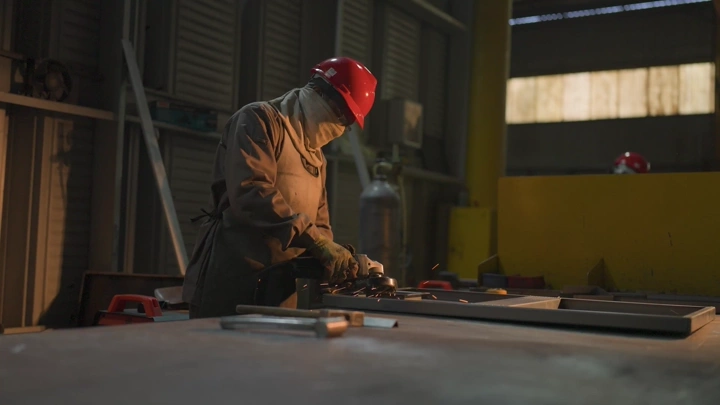 عامل يرتدي خوذة حمراء يعمل في مصنع، لقطة داخلية.