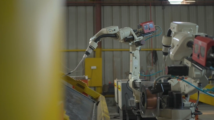Industrial robots operating in a factory, indoor shot.