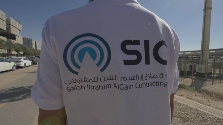 شخص يرتدي قميص شركة مقاولات في موقع بناء، لقطة نهارية.