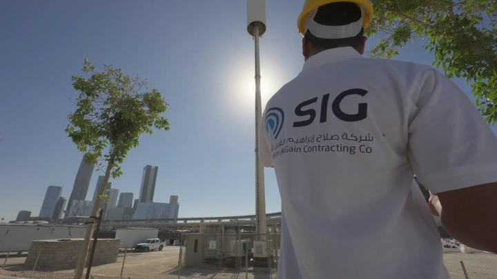 مهندس يرتدي خوذة في موقع بناء بمدينة حديثة، لقطة من الخلف.