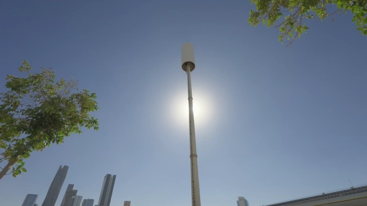 برج اتصالات في مدينة تحت السماء الزرقاء مع شخص واقف، لقطة منخفضة.