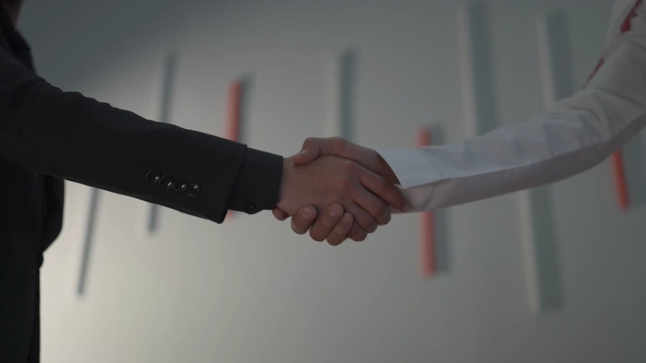 Handshake between two people in an office setting, close-up shot.