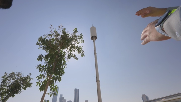 Communication tower in a city under a blue sky, low-angle shot.