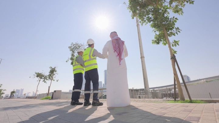 مهندسون يتحدثون في موقع بناء تحت الشمس، لقطة من الخلف.