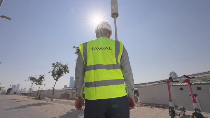 مهندس يرتدي سترة عاكسة في شارع مشمس، لقطة من الخلف.