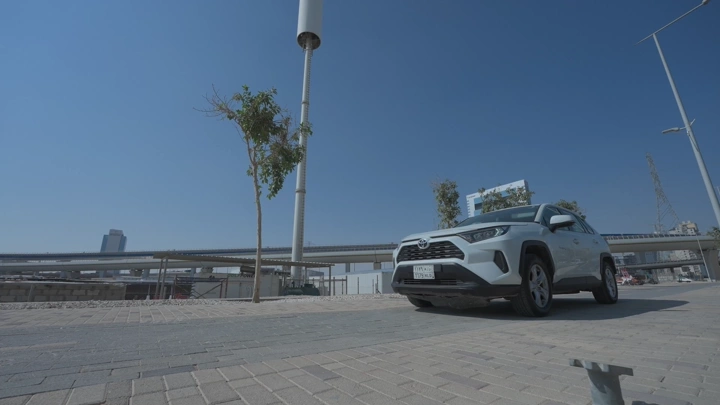 سيارة بيضاء متوقفة في شارع المدينة نهارًا، لقطة منخفضة.