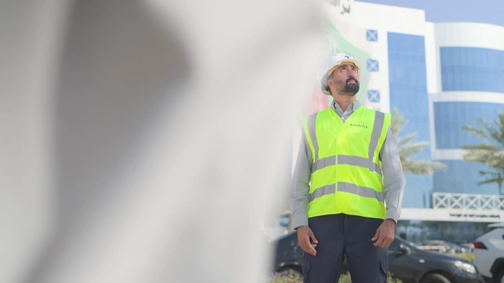 مهندس يرتدي سترة أمان أمام مبنى حديث، لقطة من زاوية منخفضة.