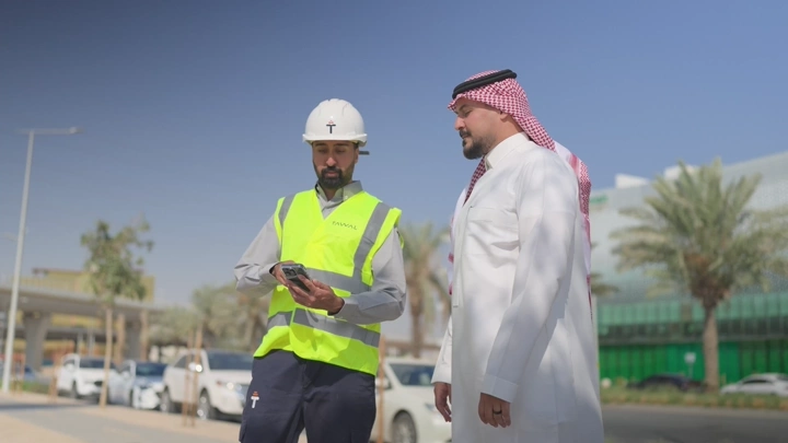 مهندسان يتناقشان في موقع بناء في وضح النهار، لقطة خارجية.