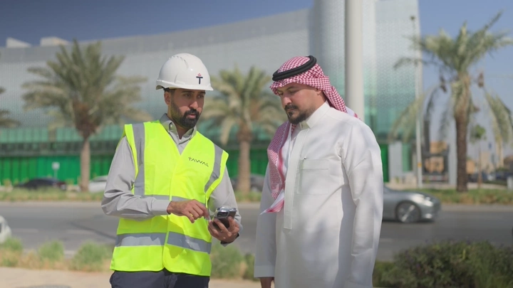 مهندسان يتناقشان في موقع بناء نهارًا، لقطة عادية.