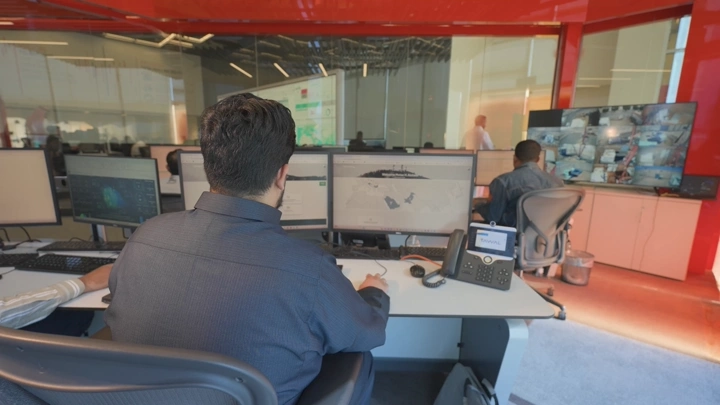 موظفون يعملون في مكتب حديث مع شاشات متعددة، لقطة داخلية.