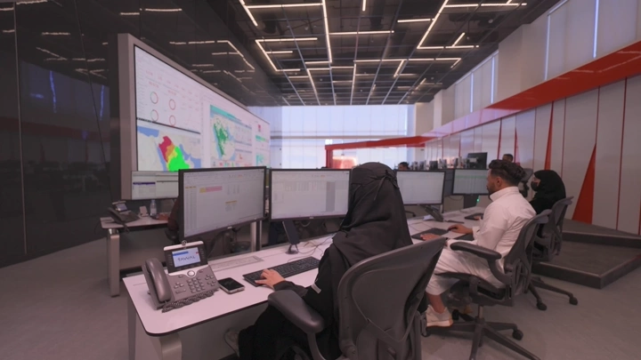 موظفون يعملون في مكتب حديث مع شاشات كبيرة، لقطة داخلية.