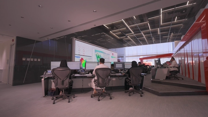 موظفون يعملون في مكتب حديث مع شاشات كبيرة، لقطة داخلية.