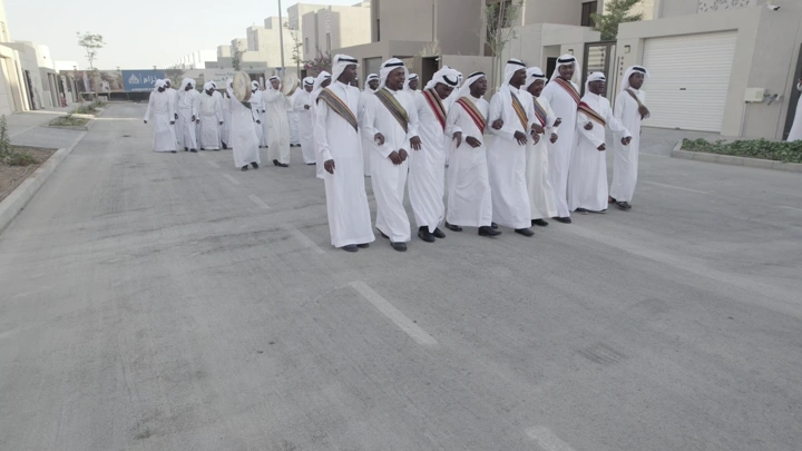 مجموعة رجال في زي تقليدي يحتفلون في شارع سكني، لقطة نهارية.