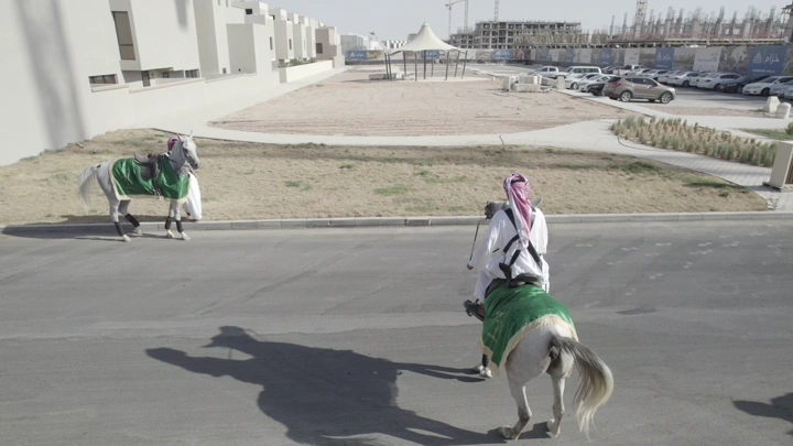فرسان على خيول في منطقة حضرية، لقطة من الجو.
