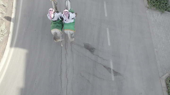 فرسان يرتدون الزي التقليدي على خيول في شارع، لقطة جوية.