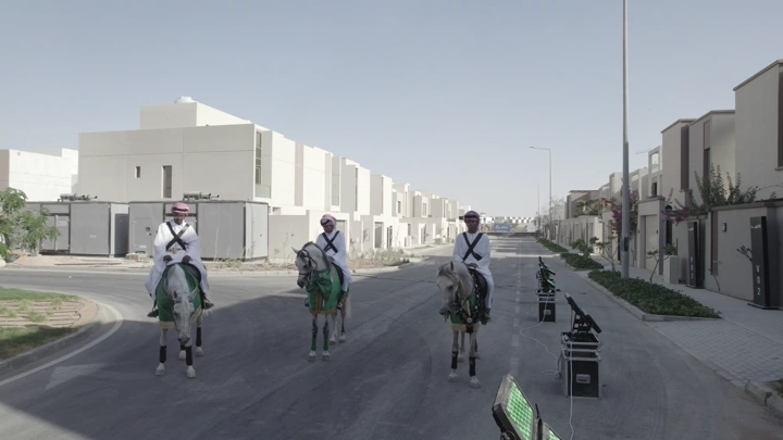 فرسان على خيول في شارع سكني، لقطة نهارية.