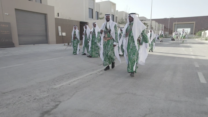 مجموعة رجال يرتدون زي تقليدي أخضر في احتفال في الشارع، لقطة واسعة.