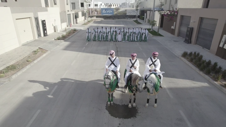 فرسان على خيول في شارع مع مجموعة من الناس في الخلفية، لقطة جوية.