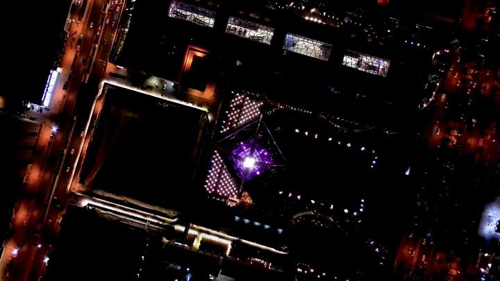 صورة جوية لبرج الفيصلية في الرياض ليلاً، بإضاءة ملونة.