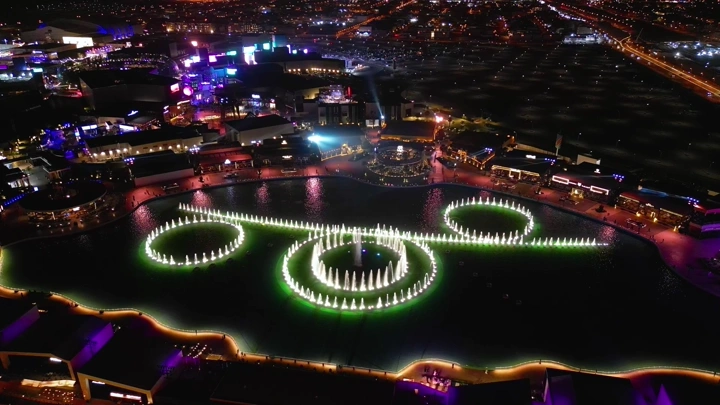 عرض نافورة مضيئة في البوليفارد الرياض ليلاً، لقطة جوية.