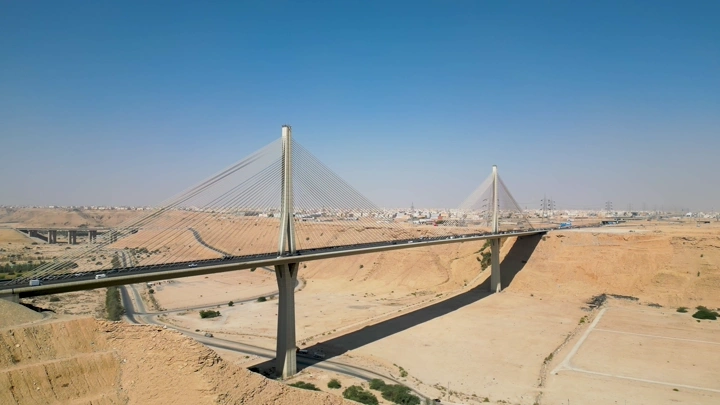 الجسر المعلق في الرياض يمتد فوق وادٍ صحراوي، صورة جوية.
