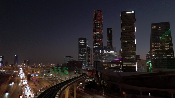 ناطحات سحاب وقطار مترو في الرياض ليلاً، لقطة جوية.