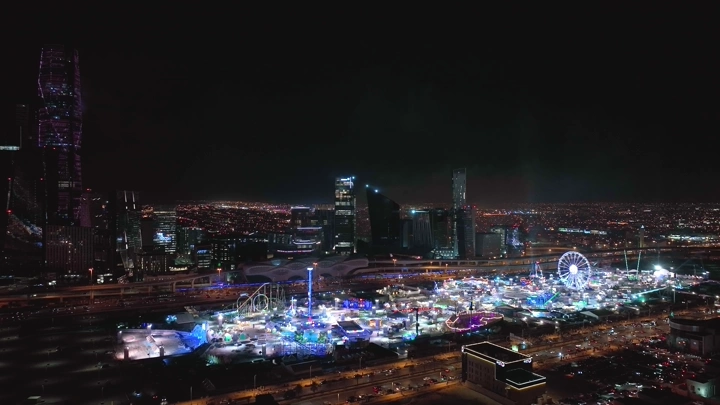 مدينة ملاهي مضاءة في الليل بالرياض، لقطة جوية.