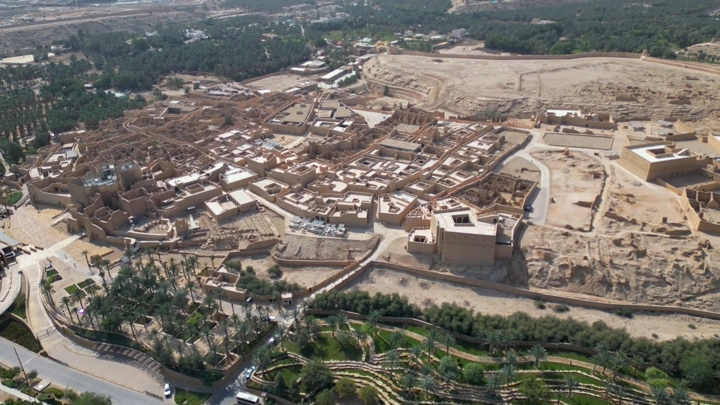 صورة جوية لمدينة الدرعية التاريخية في الرياض، تُظهر المباني الطينية والمناظر الطبيعية المحيطة.