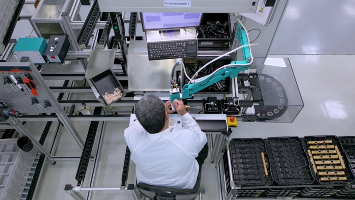 عامل في مصنع يستخدم ذراعًا آلية، لقطة من الأعلى.