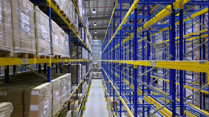 مستودع كبير مع رفوف معدنية وصناديق تخزين، لقطة داخلية.