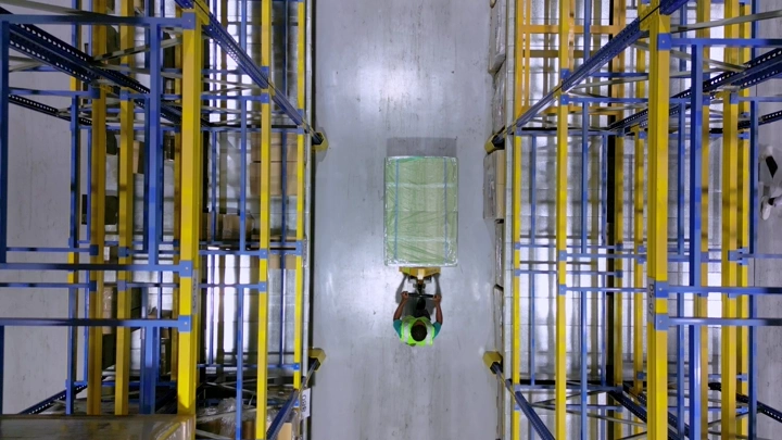 عامل في مستودع بين رفوف التخزين، لقطة علوية.