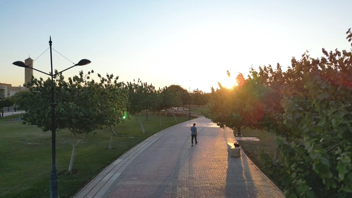 شخص يمشي في حديقة عياف بالرياض عند غروب الشمس، لقطة جوية.