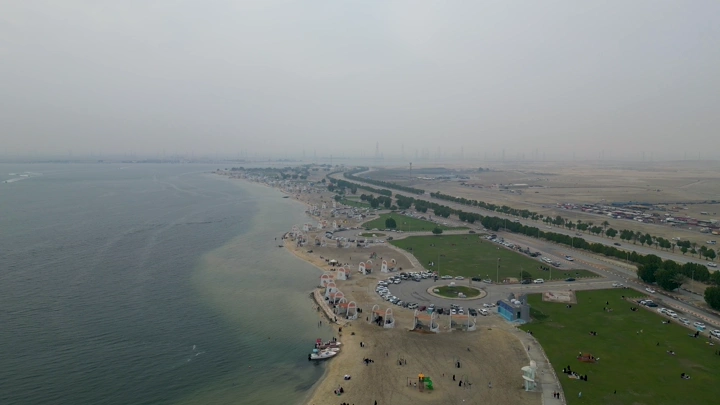 شاطئ نصف القمر في الدمام من الجو، يظهر البحر والمنتزهات.