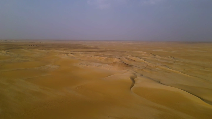 كثبان رملية في صحراء النفود تحت سماء غائمة، لقطة جوية.