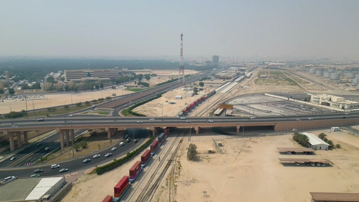 قطار بضائع يسير في الأحساء تحت جسر، لقطة جوية.