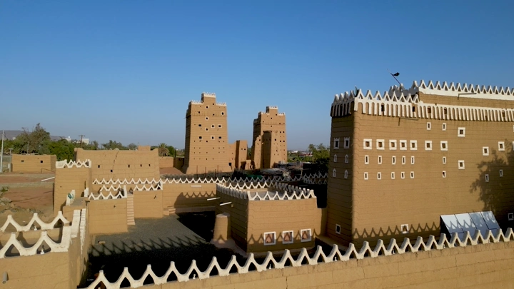 قصر طيني تقليدي في نجران تحت سماء زرقاء، لقطة نهارية.