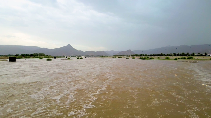 سيل في نجران مع جبال في الخلفية، لقطة واسعة.
