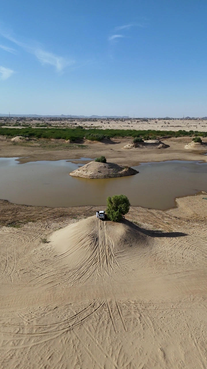 Lake Najran in the desert with a car on a sandy hill, aerial shot.