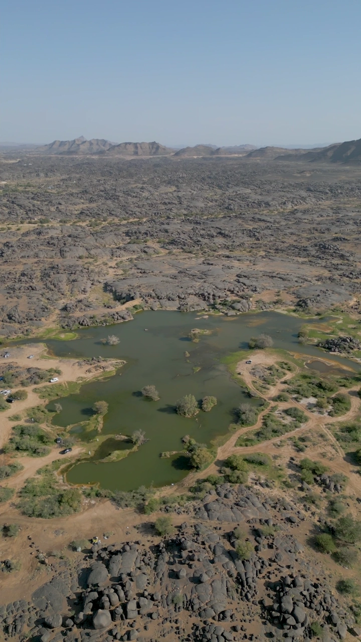 منظر جوي لبئر عسكر في نجران، يظهر تضاريس صخرية ومسطحات مائية.