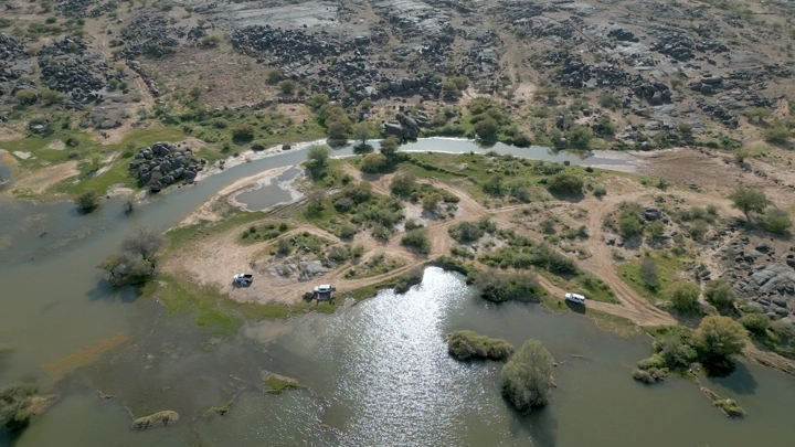 منظر جوي لمنطقة بئر عسكر في نجران، يظهر المياه والأشجار والصخور.