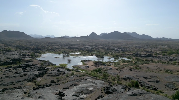 منظر جوي لمنطقة بئر عسكر في نجران، يظهر التضاريس الجبلية والبرك المائية.