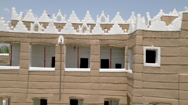 قصر طيني تقليدي في نجران تحت سماء زرقاء، لقطة نهارية.