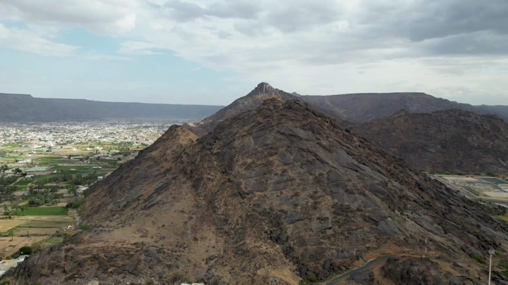 جبل صخري في نجران مع خلفية سحابية، لقطة جوية.