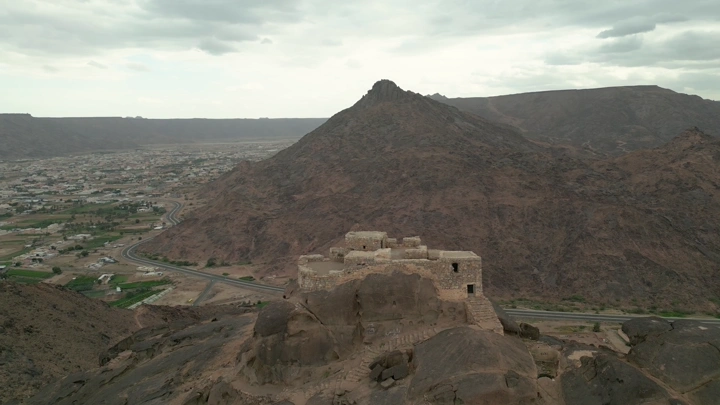 قلعة رعوم في نجران مع الجبال في الخلفية، لقطة جوية.