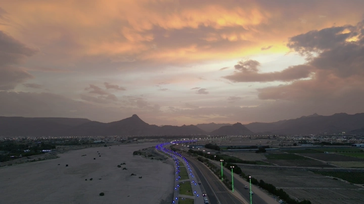 طريق مضاء في نجران عند الغروب، لقطة جوية.