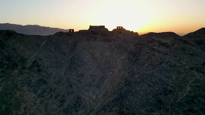 جبال مع مبانٍ قديمة عند الغروب، لقطة جوية.